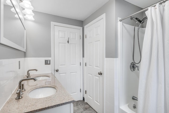 bathroom with double vanity, shower / bath combo, a sink, and tile walls