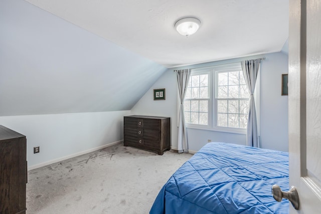 bedroom with lofted ceiling, light colored carpet, and baseboards