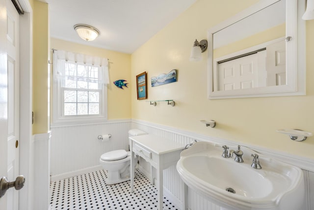 bathroom featuring wainscoting, a sink, and toilet