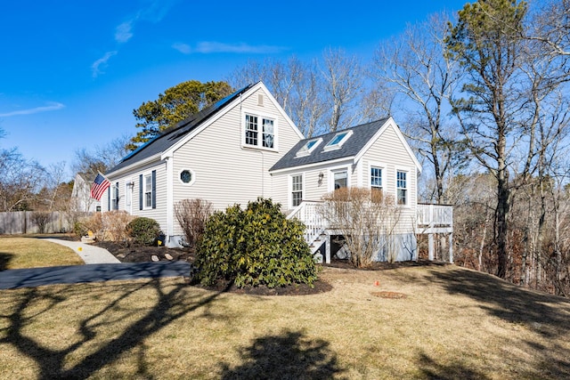 view of side of property featuring a deck, fence, aphalt driveway, and a yard