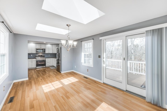 unfurnished dining area with a skylight, visible vents, and an inviting chandelier