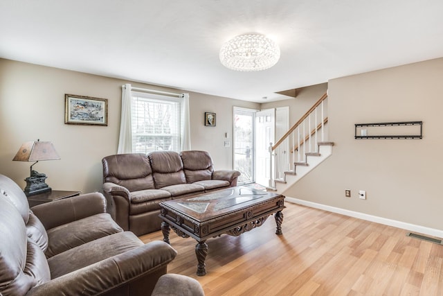 living area featuring visible vents, light wood-style flooring, baseboards, and stairs