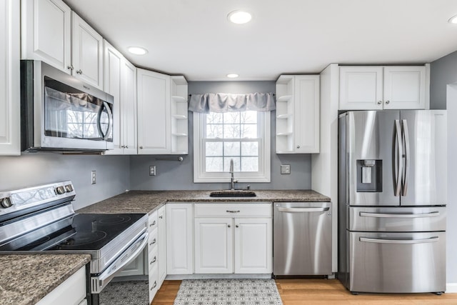 kitchen featuring appliances with stainless steel finishes, white cabinetry, a sink, and open shelves