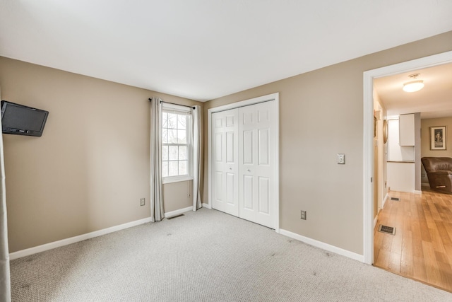 unfurnished bedroom featuring carpet floors, baseboards, visible vents, and a closet