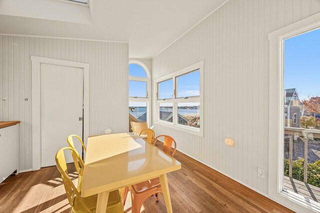 dining room featuring wood-type flooring, a wealth of natural light, and wooden walls