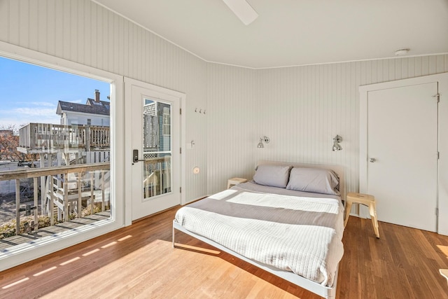 bedroom with wood walls, access to outside, and wood-type flooring