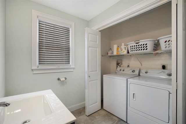 clothes washing area featuring laundry area, light tile patterned floors, baseboards, washer and clothes dryer, and a sink