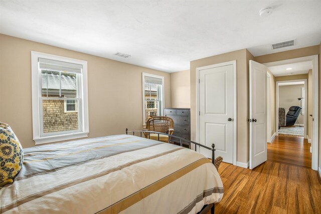 bedroom with a closet, visible vents, baseboards, and wood finished floors