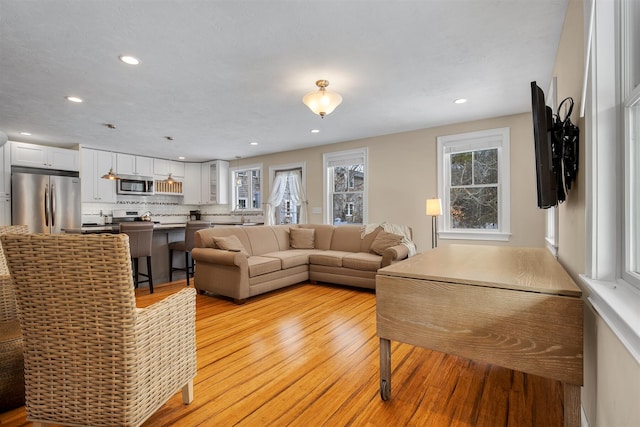 living area with light wood-style flooring and recessed lighting