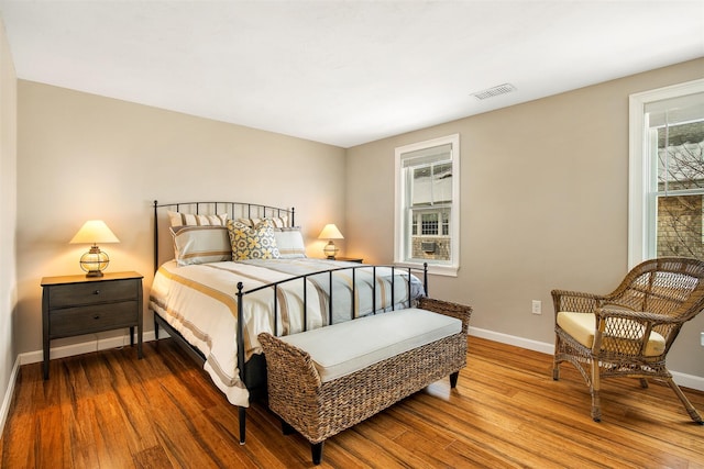 bedroom with wood finished floors, visible vents, and baseboards