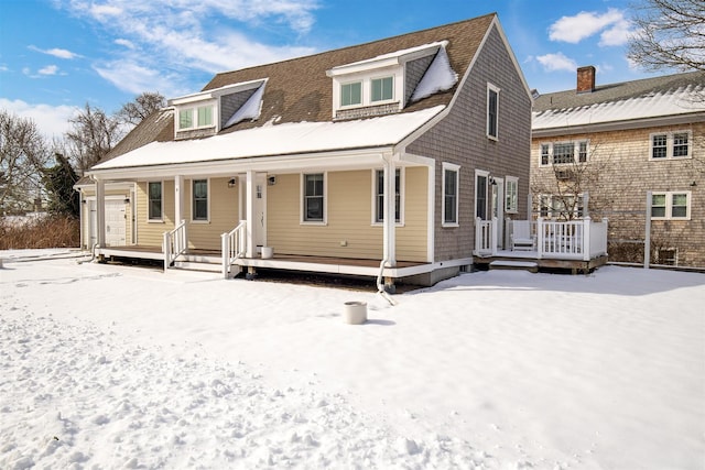 snow covered back of property featuring covered porch