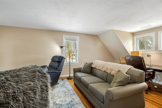 interior space with lofted ceiling, visible vents, baseboards, and wood finished floors