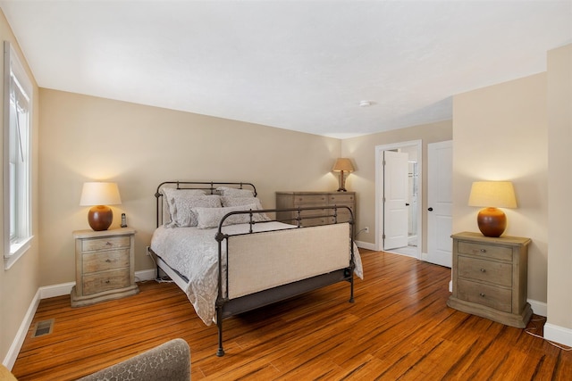 bedroom with visible vents, baseboards, and wood finished floors