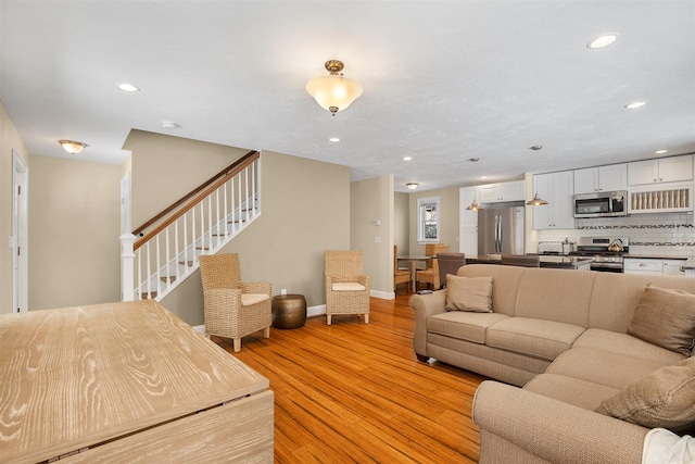 living area featuring light wood-type flooring, baseboards, stairway, and recessed lighting