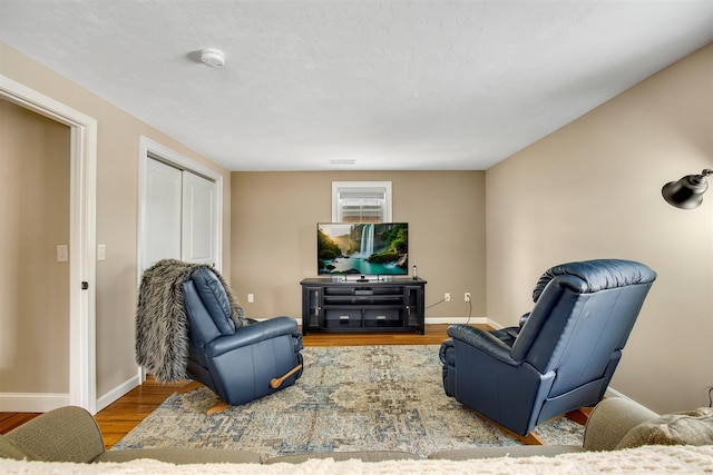 living area featuring visible vents, baseboards, and wood finished floors