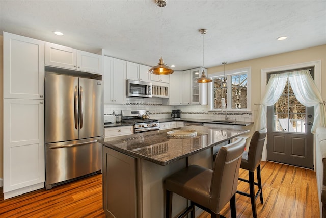 kitchen with appliances with stainless steel finishes, wood finished floors, white cabinetry, and tasteful backsplash