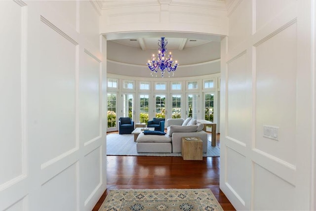 interior space with a towering ceiling, dark wood-type flooring, crown molding, a notable chandelier, and beam ceiling