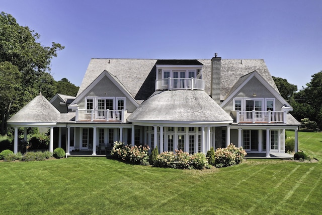 rear view of house with a balcony and a lawn