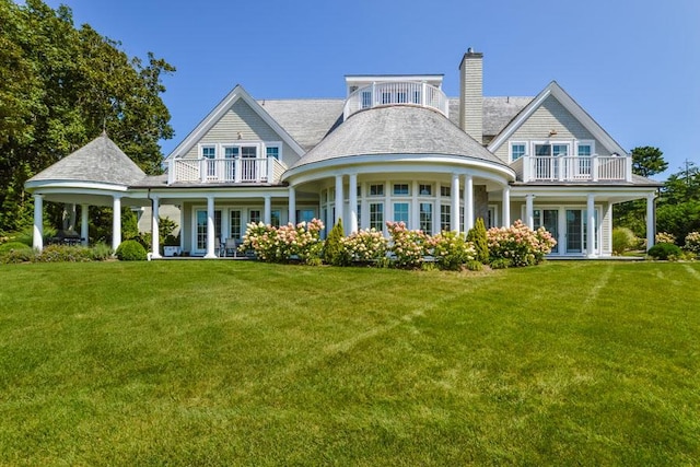 rear view of property with a balcony and a yard