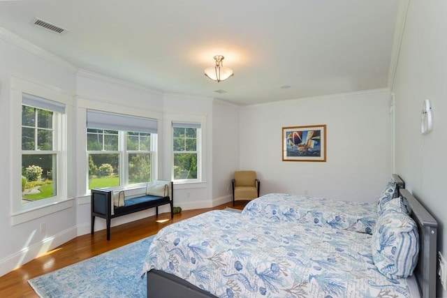 bedroom with hardwood / wood-style floors, crown molding, and multiple windows