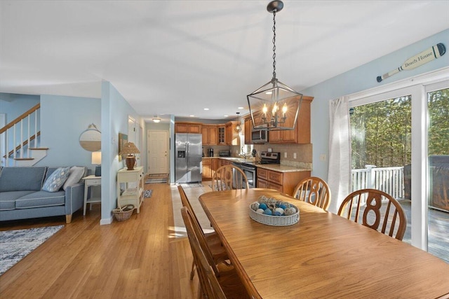 dining space featuring recessed lighting, a notable chandelier, light wood finished floors, and stairs