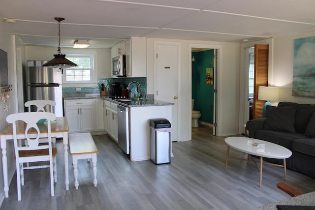 kitchen with white cabinets, stainless steel appliances, tasteful backsplash, sink, and hanging light fixtures