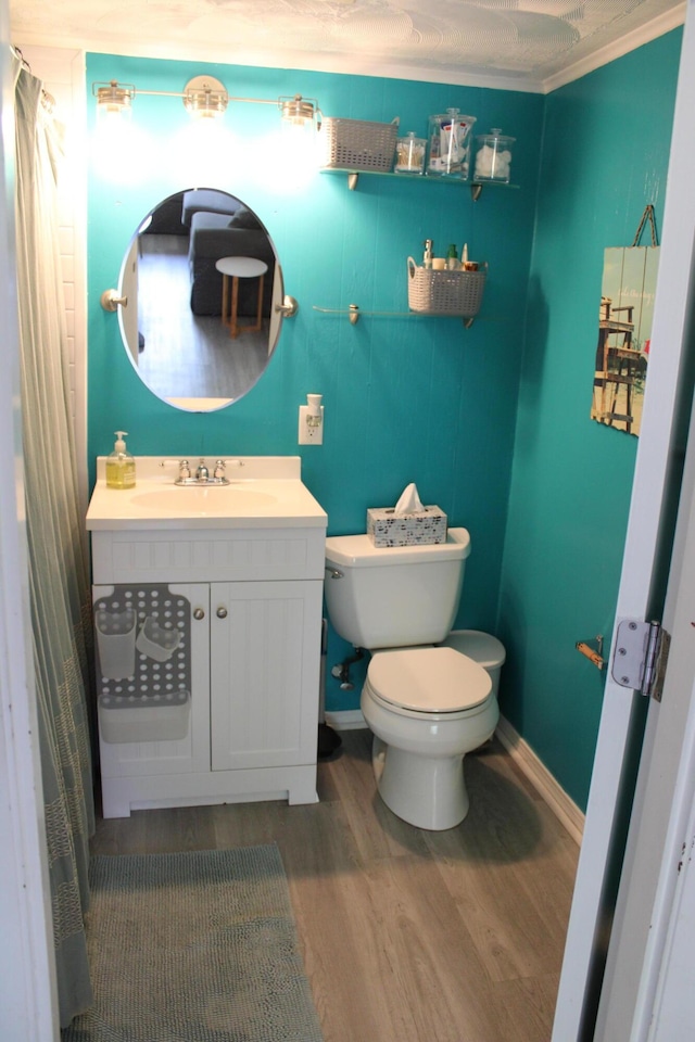 bathroom featuring crown molding, hardwood / wood-style flooring, toilet, and vanity