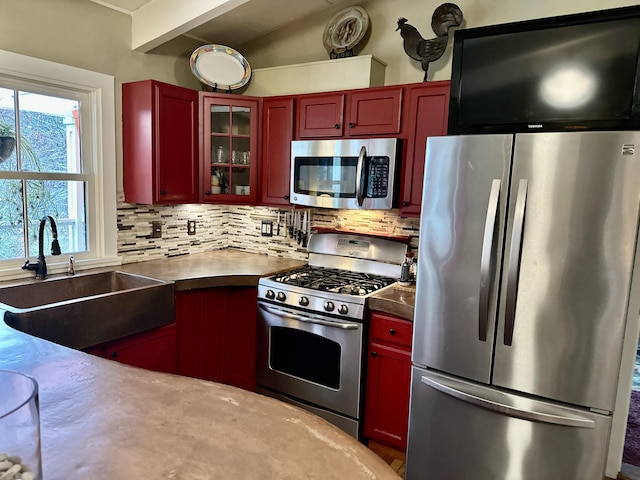 53 Highland Rd, North Truro, MA 02652 - kitchen with stainless steel appliances, reddish brown cabinets, a sink, decorative backsplash, and glass insert cabinets