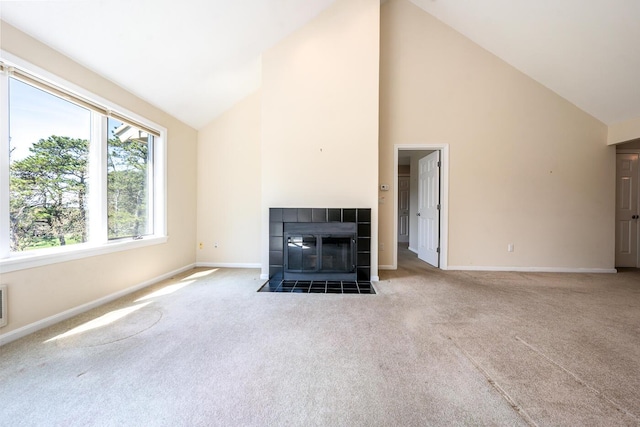 unfurnished living room with carpet, baseboards, high vaulted ceiling, and a tile fireplace