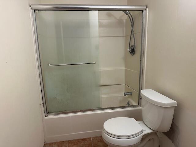 bathroom with toilet, shower / bath combination with glass door, and tile patterned floors