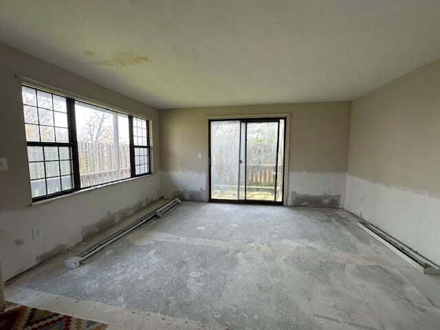 empty room with baseboard heating and unfinished concrete flooring