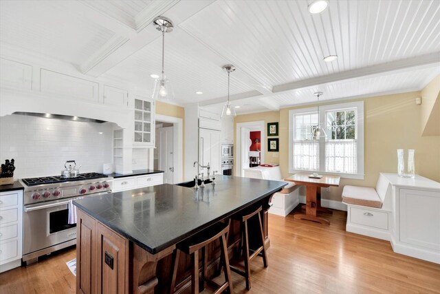 kitchen with white cabinets, a center island with sink, appliances with stainless steel finishes, and pendant lighting