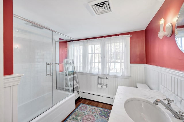 full bathroom with baseboard heating, shower / bath combination with glass door, vanity, toilet, and hardwood / wood-style flooring