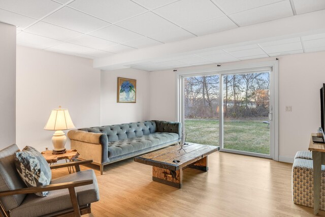 living room with baseboards, light wood finished floors, and a paneled ceiling
