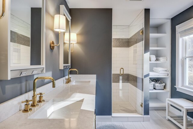 bathroom with a shower stall, a sink, and a healthy amount of sunlight