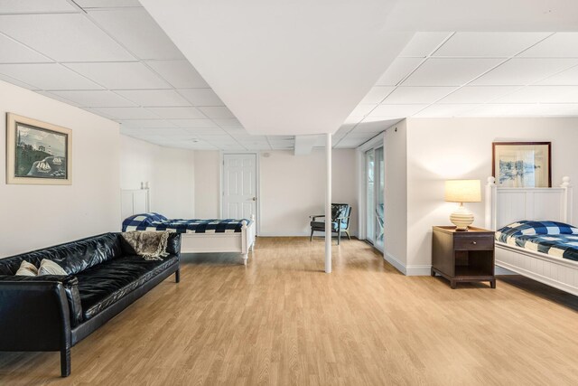 interior space featuring baseboards, light wood-style flooring, and a drop ceiling