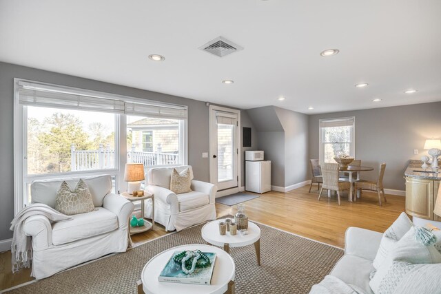 living area featuring light wood finished floors, baseboards, visible vents, and recessed lighting