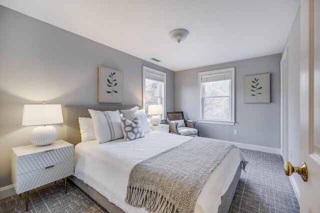 bedroom with baseboards, visible vents, and dark carpet