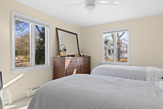 bedroom featuring ceiling fan, a baseboard heating unit, and light carpet