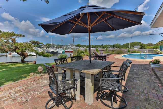 view of patio with a fenced in pool, exterior bar, and a water view