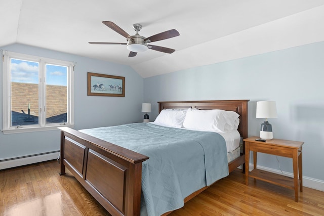 bedroom featuring ceiling fan, a baseboard heating unit, light wood-type flooring, and vaulted ceiling