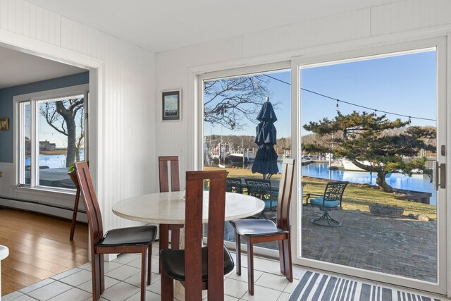 tiled dining area with a baseboard heating unit and a water view
