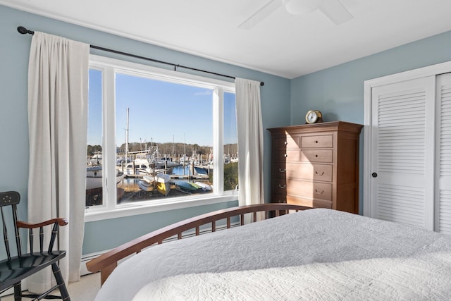 bedroom featuring ceiling fan, multiple windows, a closet, and a water view