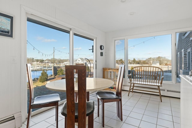 sunroom / solarium featuring baseboard heating, a water view, and a healthy amount of sunlight