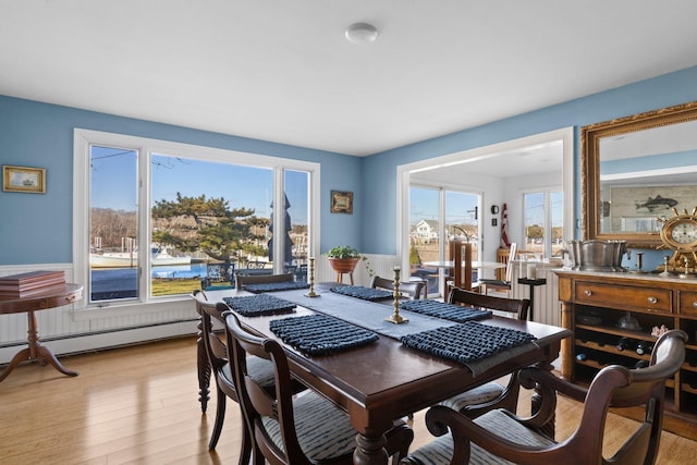 dining space featuring a healthy amount of sunlight, light hardwood / wood-style flooring, and a baseboard heating unit