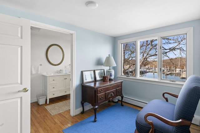 living area with sink, a water view, light hardwood / wood-style flooring, and baseboard heating