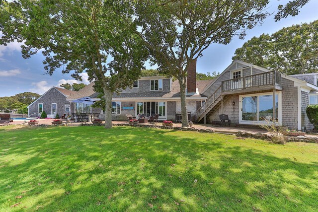 rear view of property with a patio area, a wooden deck, a lawn, and a pergola