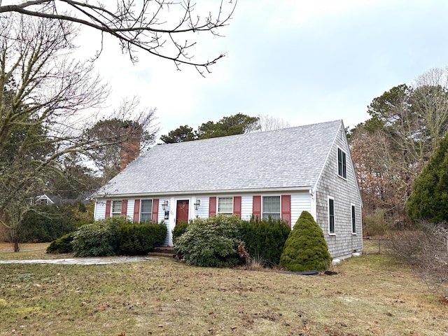 view of front of home with a chimney, a front lawn, and roof with shingles