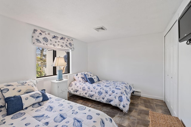 bedroom featuring baseboard heating, a closet, and visible vents