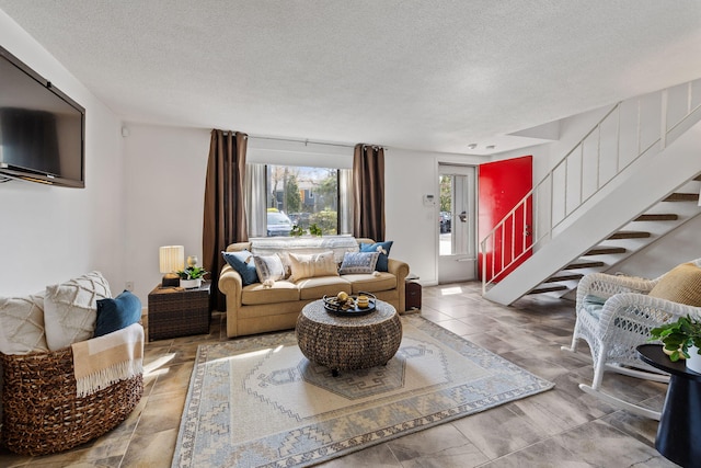 living area featuring stairway, radiator heating unit, and a textured ceiling